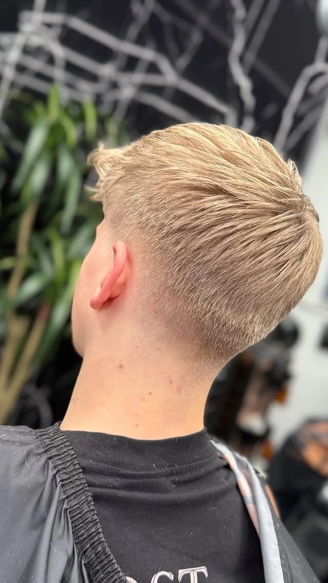 The barber at work — precision scissor cut in warm, low light